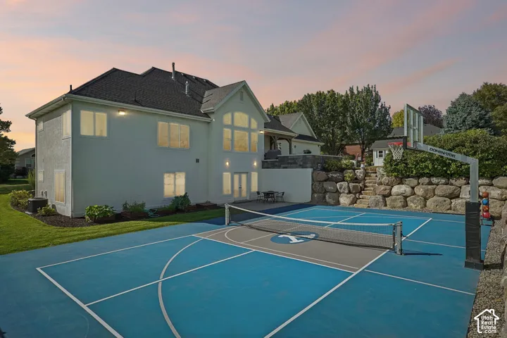 Multi-sport court with basketball hoop, terraced landscaping with stone retaining walls, and a private patio area