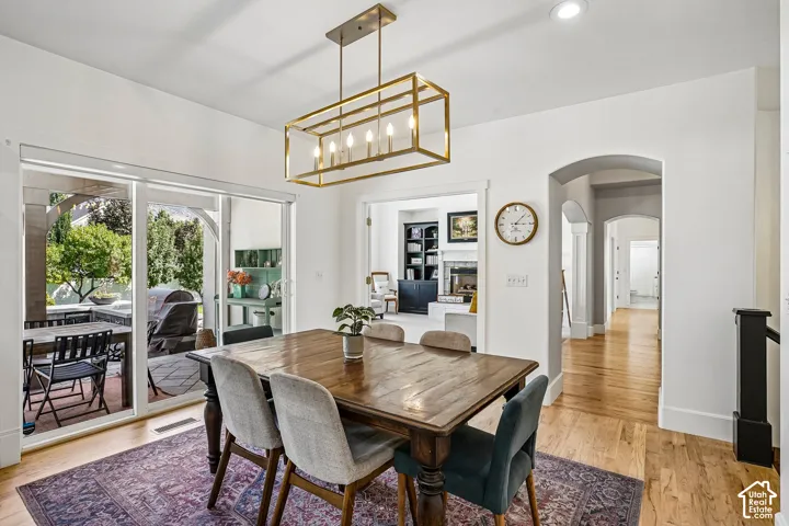 Hardwood flooring, arched doorways, a coffered ceiling, and a prominent rectangular chandelier