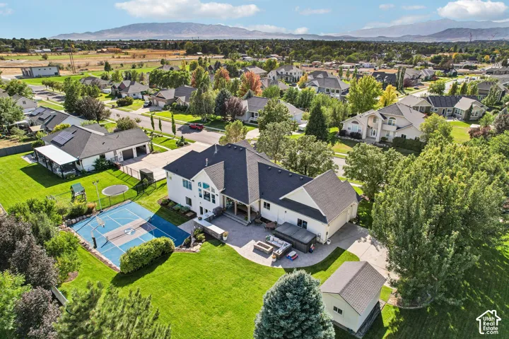 Expansive property with a private sports court, lush green lawn, mature trees, and a detached storage shed