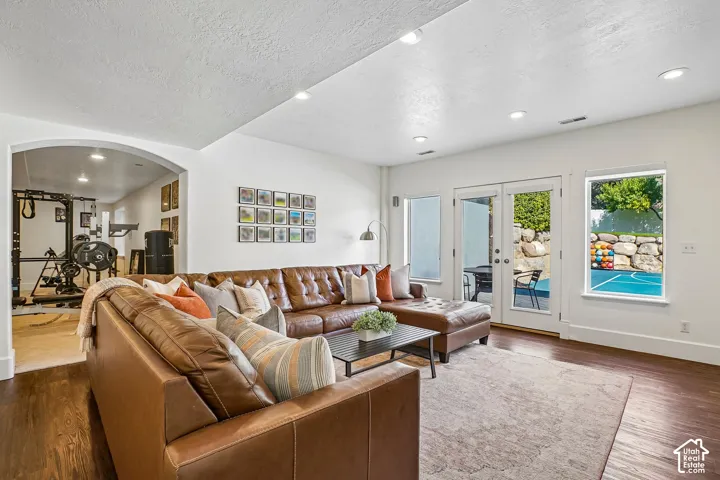 Wood-finish flooring, recessed lighting, arched entryway, French doors, and an outdoor sport court