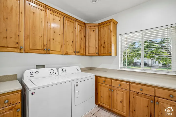 Laundry area featuring wood cabinetry, light-toned countertops, and a window with blinds