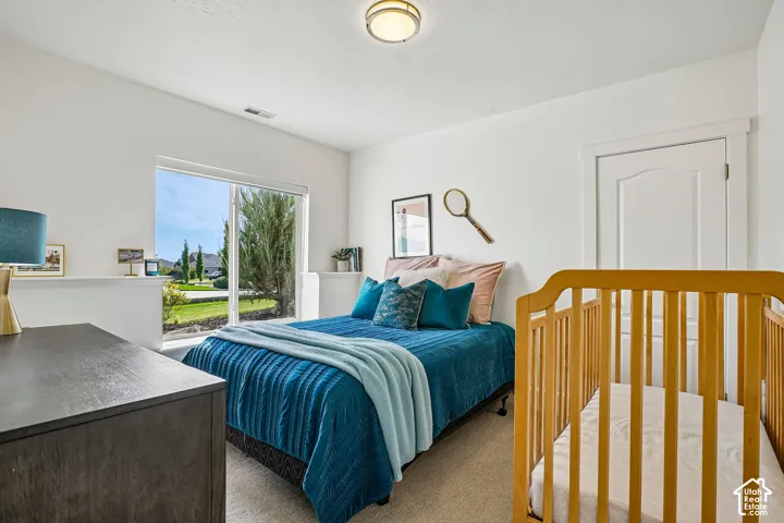 Bright room with a large window, light-colored carpet, white walls, and a ceiling-mounted light fixture