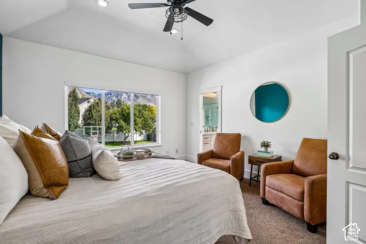 Vaulted ceiling with recessed lighting and ceiling fan, large window with mountain backdrop, carpet flooring, and a full bathroom with double vanity