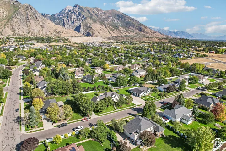Residential neighborhood featuring mature trees, paved streets, and mountain backdrops