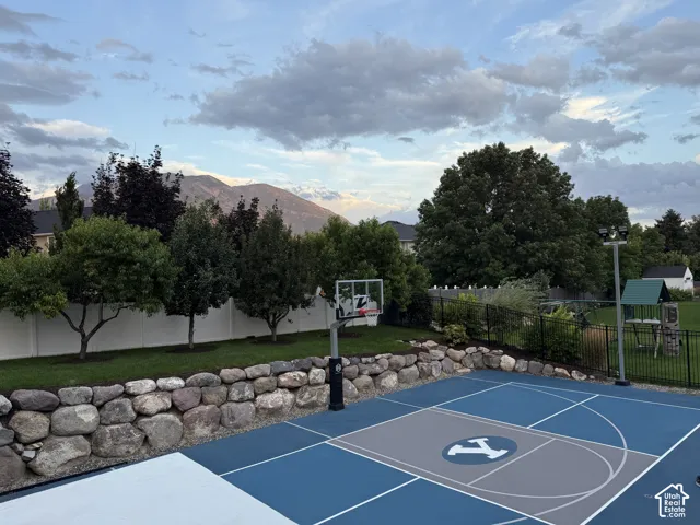 Custom-designed basketball court with a painted surface, surrounded by a stone retaining wall and a black metal fence