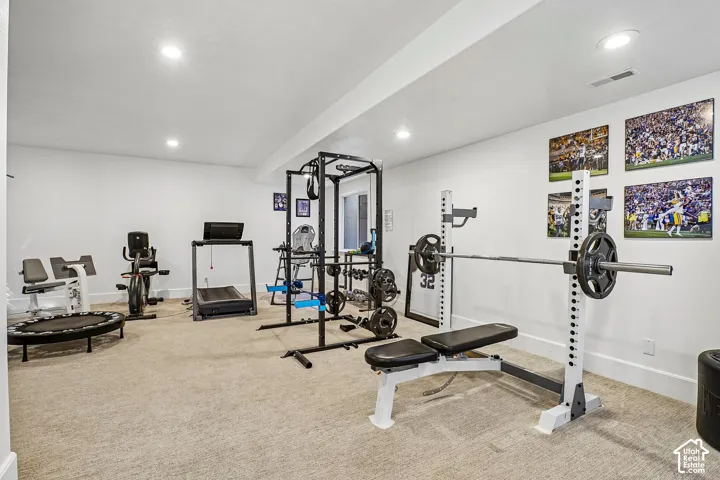 Carpeted exercise room with recessed lighting and painted white walls