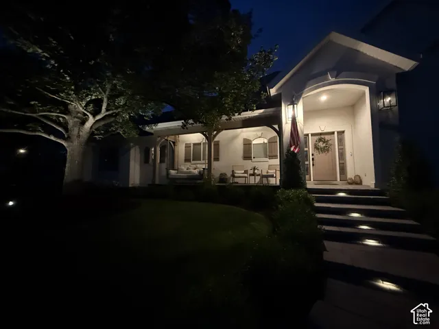 Covered entry with recessed lighting, stone steps with integrated lighting, and a covered porch with exposed wood beams