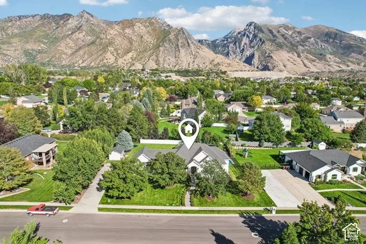 Expansive mountain backdrop, suburban setting, mature trees, manicured lawns, paved street frontage