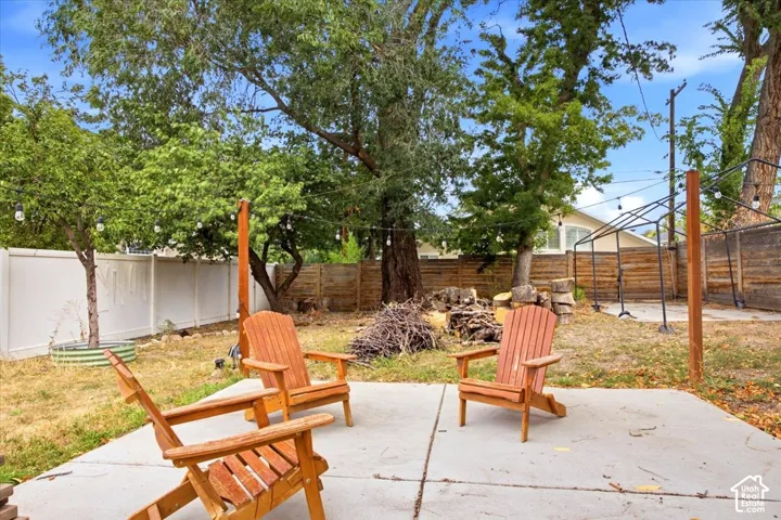 Concrete patio area with string lighting and surrounding mature trees