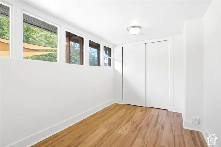 Multiple clerestory windows, wood-finish flooring, and white sliding closet doors