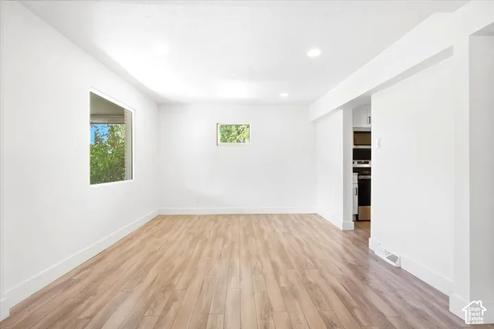White walls featuring wood-finish flooring and recessed lighting