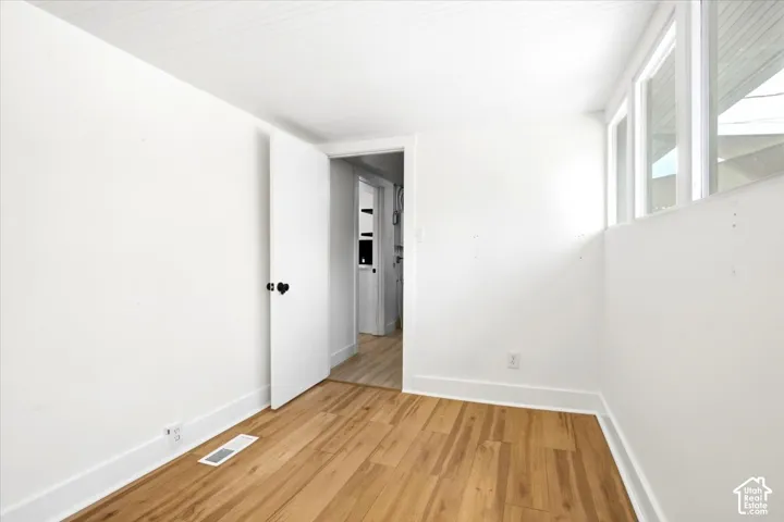 Wood-finish flooring with white trim, multiple windows, and a white paneled ceiling