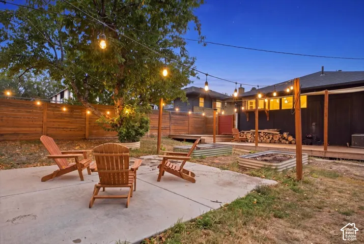Expansive backyard featuring a concrete patio, wood privacy fencing, and a built-in wood deck