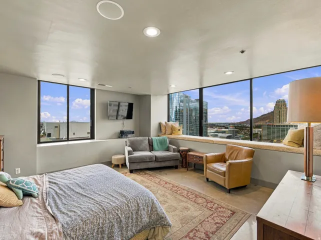 Floor-to-ceiling windows with expansive city and mountain scenery, recessed ceiling lighting, built-in window seating, and light-toned walls
