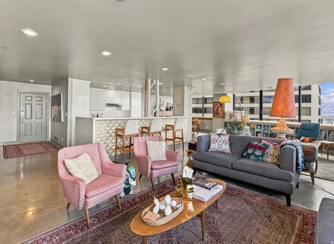 Open-concept living space featuring concrete flooring, a breakfast bar with decorative paneling, recessed lighting, and expansive windows