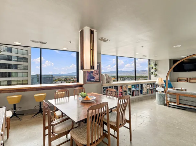 Expansive window wall with integrated shelving, built-in window seating, and concrete flooring