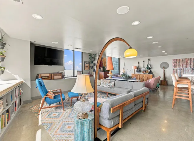 Expansive living area with polished concrete flooring, extensive recessed lighting, and a built-in window bench with shelving