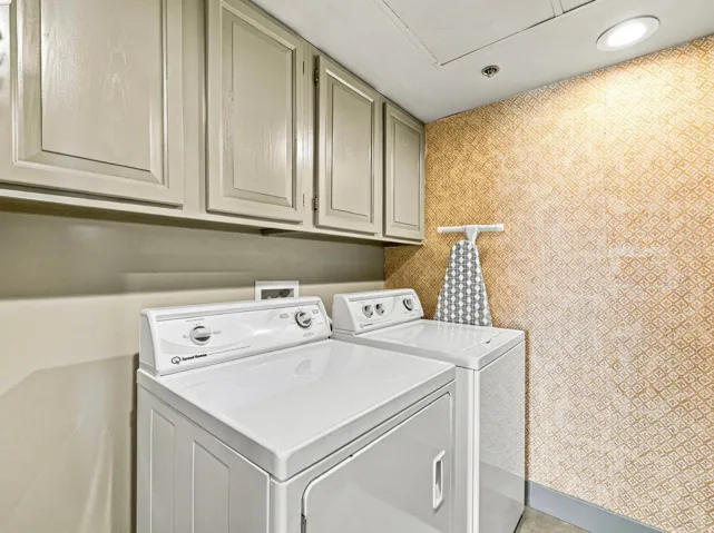 Built-in cabinetry with panel detailing, patterned wall covering, recessed ceiling lighting, and a white clothes dryer