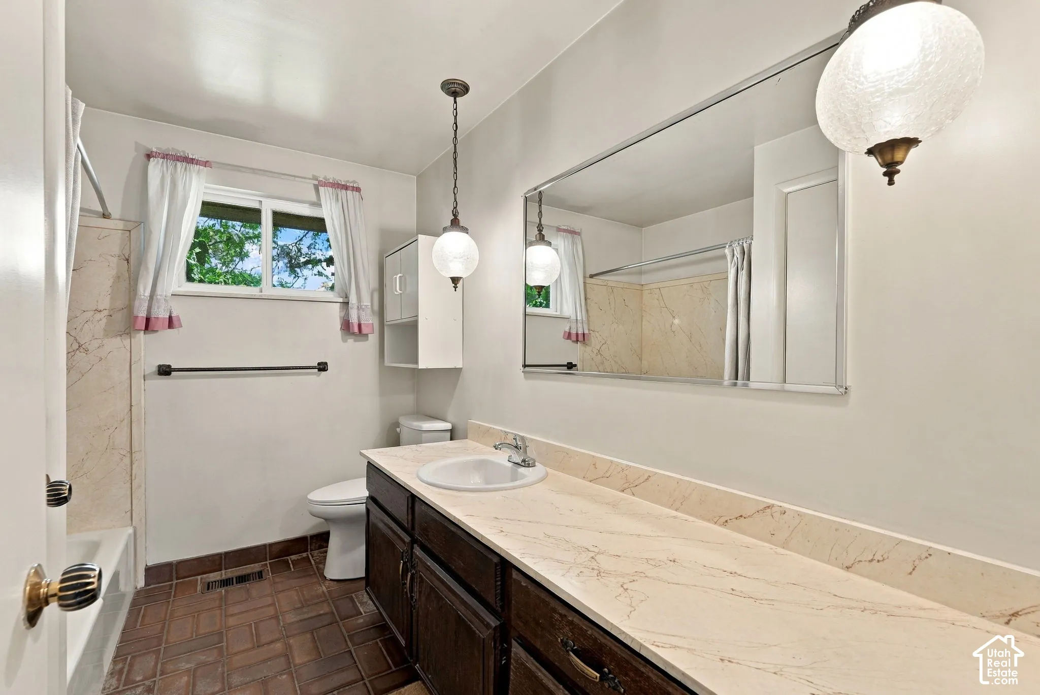 Spa-inspired primary bathroom featuring dual vanity with light wood countertops, an oversized framed mirror, and pendant lighting