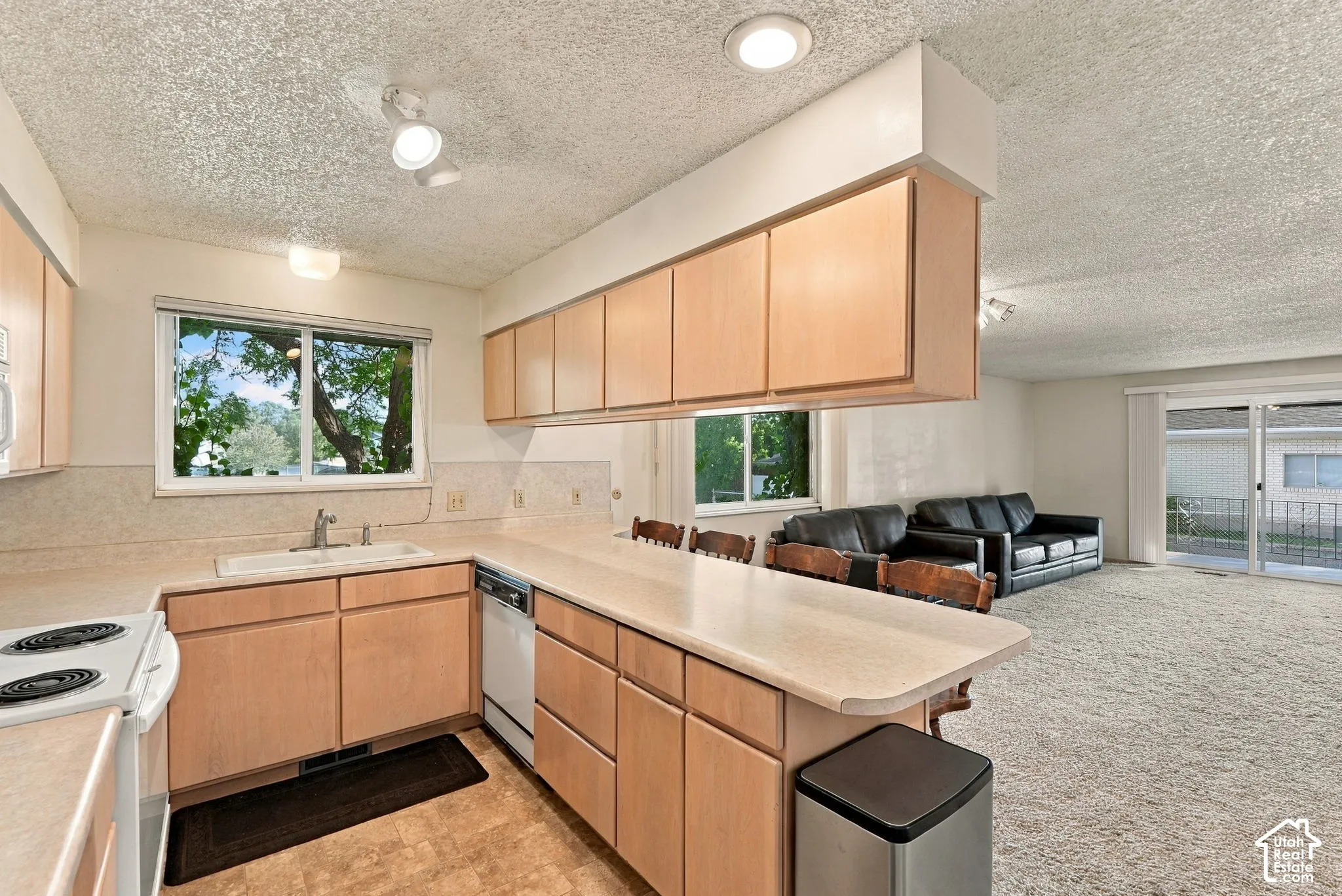 Kitchen featuring light wood-finish cabinetry, light-toned countertops, and a white sink