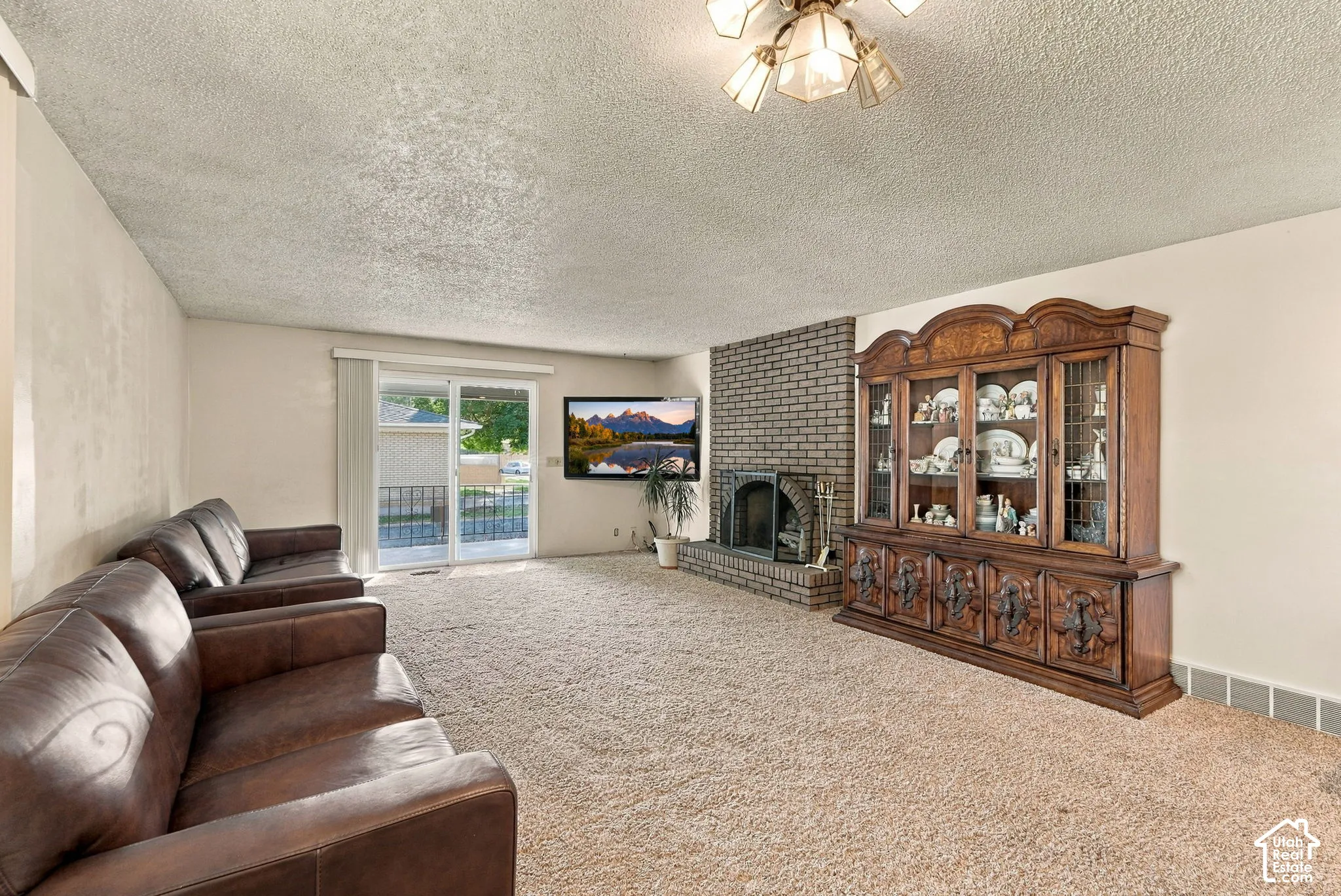 Living area featuring a brick fireplace, sliding glass door, and textured ceiling