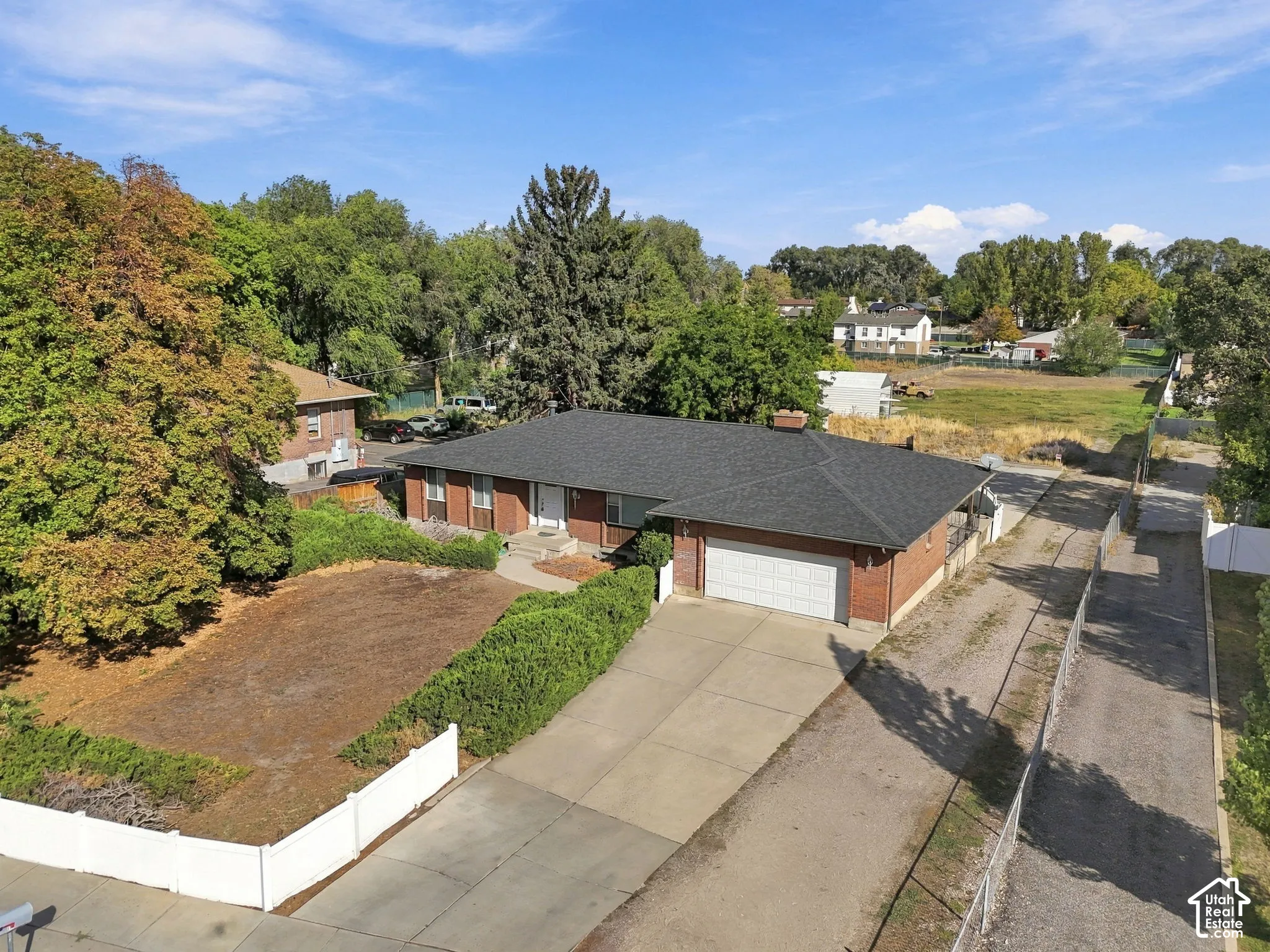 Brick exterior with white trim, attached garage, dark shingle roof, and established landscaping
