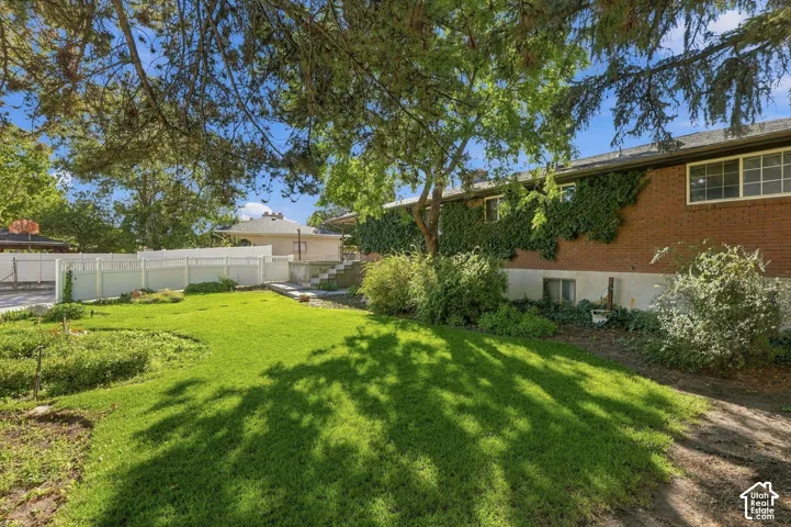 Expansive lawn area with mature trees, brick exterior, multiple windows, and extensive landscaping