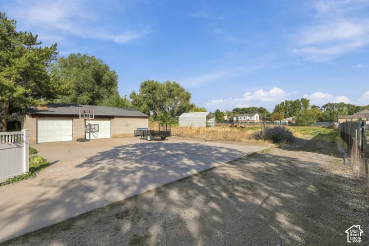 Detached two-car garage with overhead doors, concrete driveway, and white picket fencing