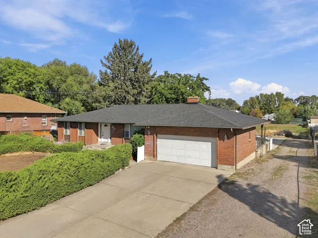 Brick exterior residence featuring a dark shingle roof and an attached two-car garage