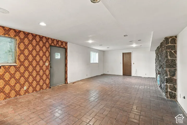 Spacious room featuring brick flooring and stone accent wall