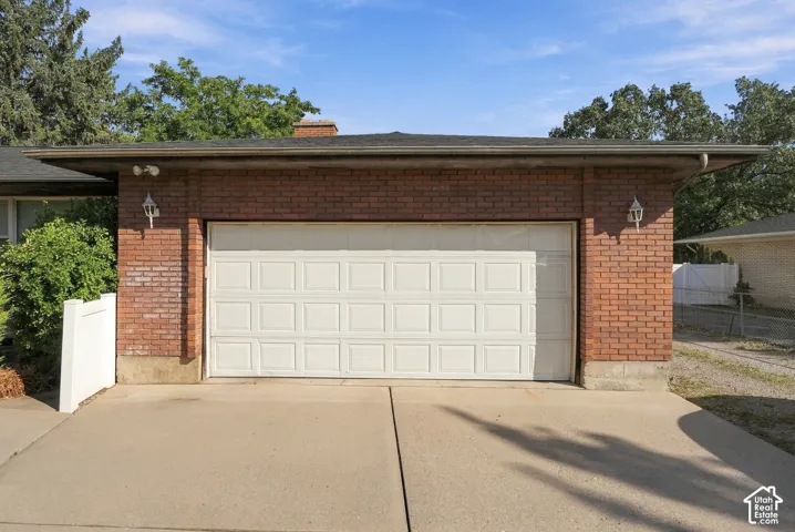 Brick exterior with a white panel garage door, complemented by two exterior sconce lights and a concrete driveway