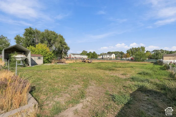 Expansive open lot with a storage shed and an open-sided carport structure