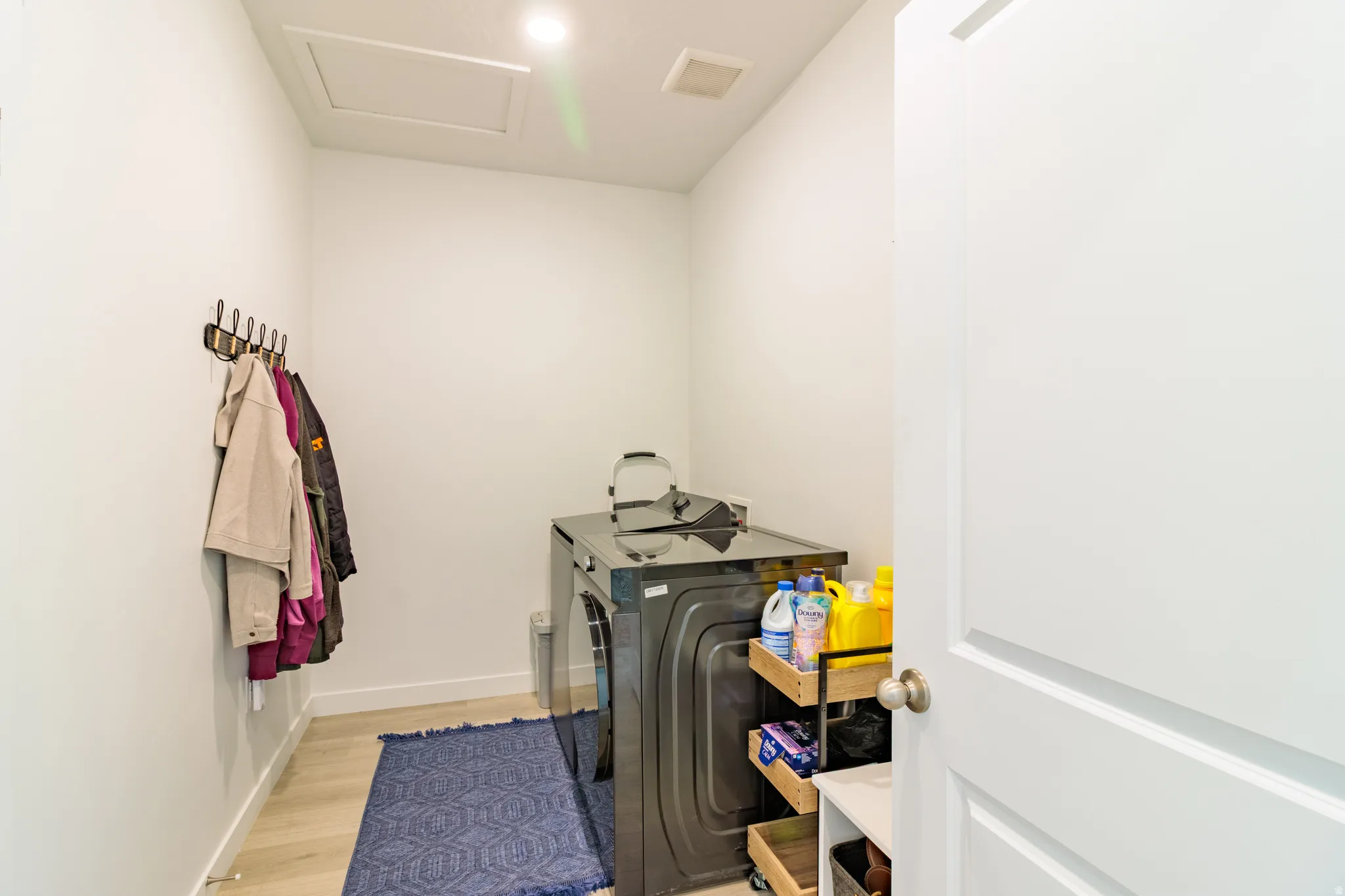 Recessed lighting illuminates this utility space, featuring light wood-finish flooring and a functional coat rack