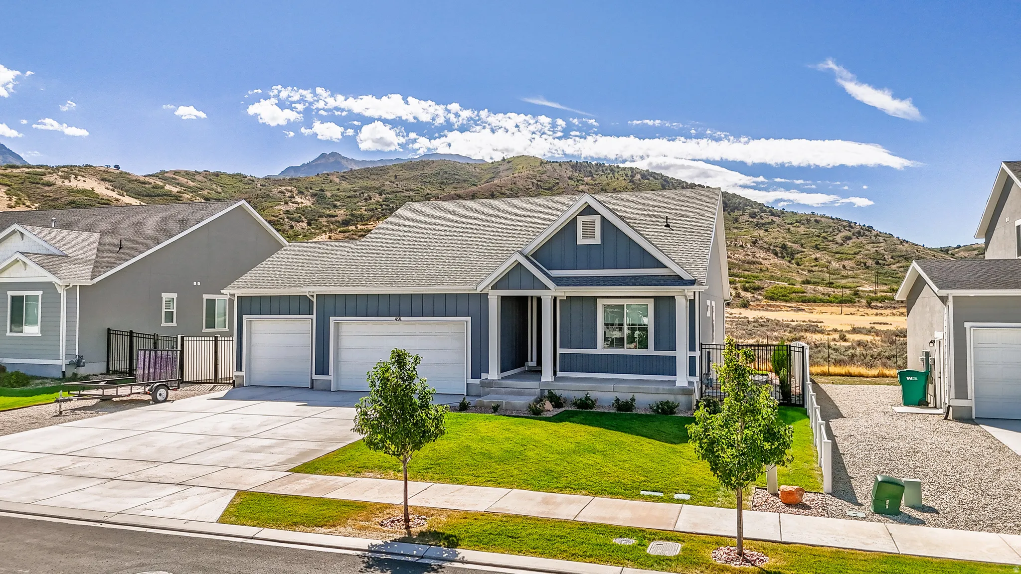Contemporary-style residence with dark blue siding, a two-car garage, and a manicured lawn