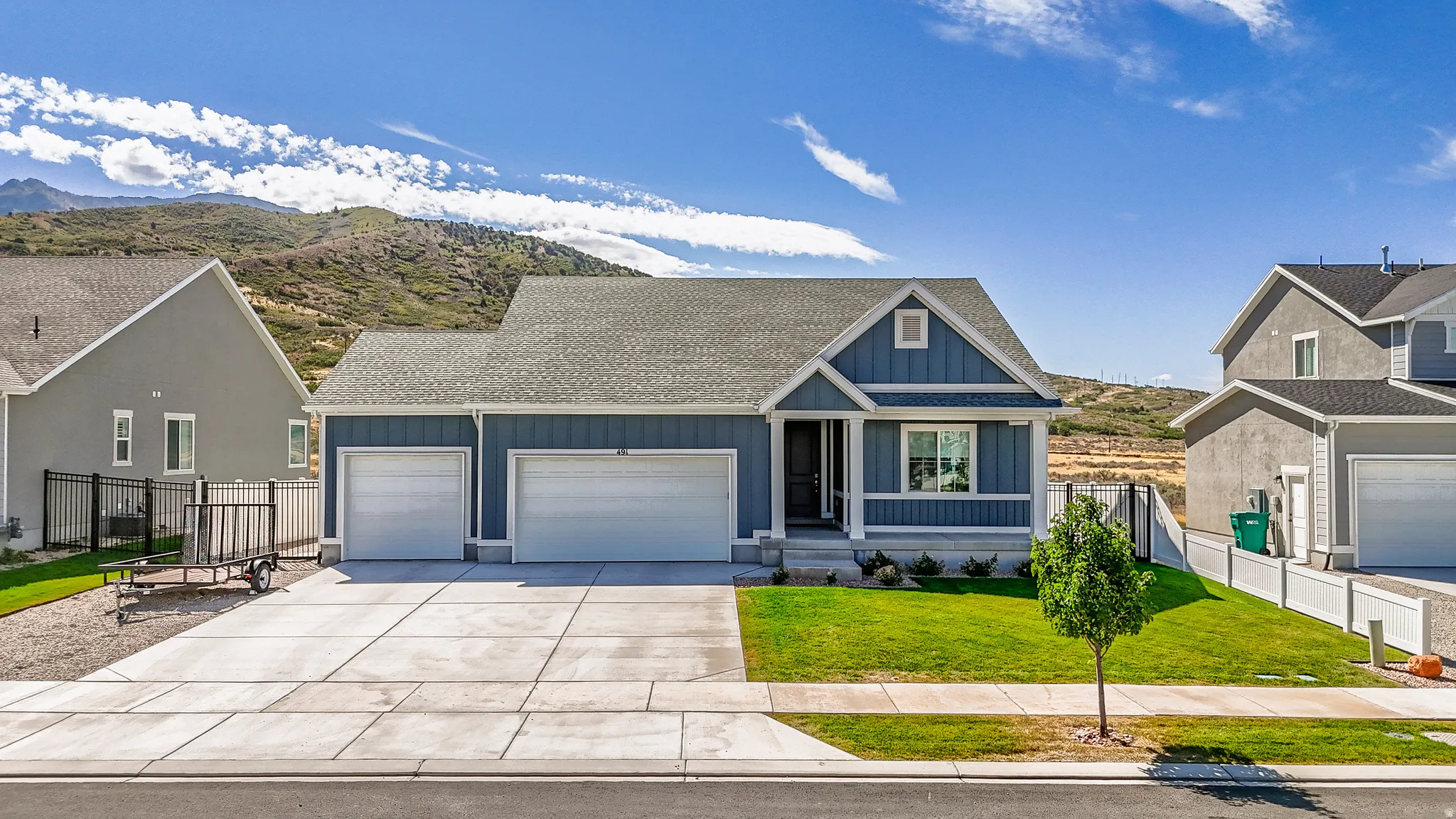Cottage-style home with a dark blue exterior, white trim, attached two-car garage, and concrete driveway