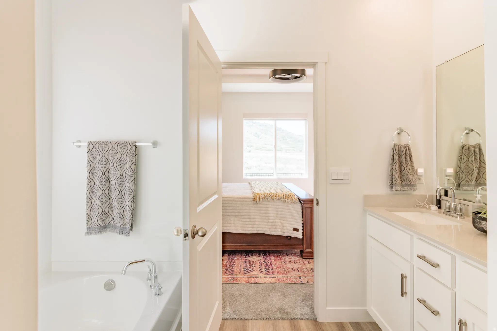 White vanity with undermount sink, chrome faucet, and integrated mirror