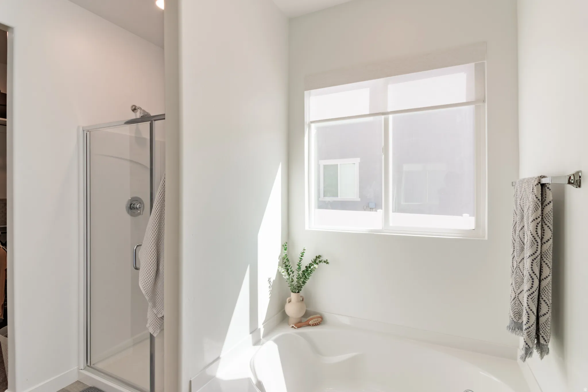 Built-in soaking tub, glass-enclosed shower, and a large window with privacy blinds