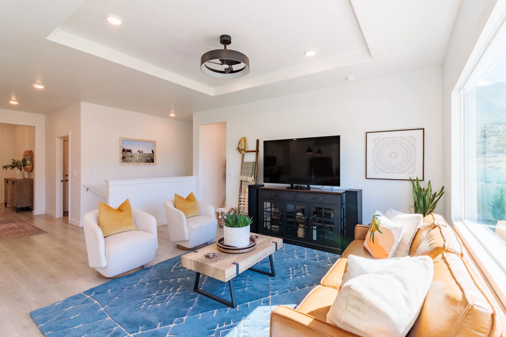 Tray ceiling with a modern ceiling fan, recessed lighting, and wood-finish flooring