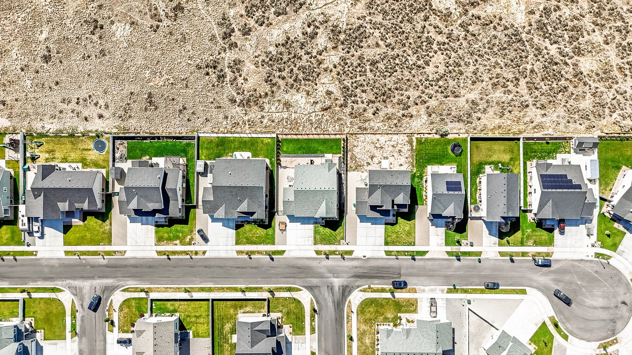 Residential community featuring single-family homes with private yard spaces, paved roadways, and integrated sidewalks