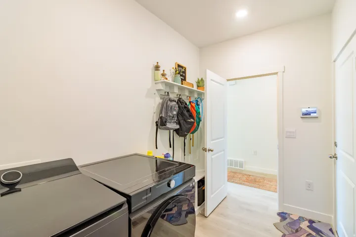 White walls, wood-finish flooring, built-in shelving with hooks, and recessed lighting