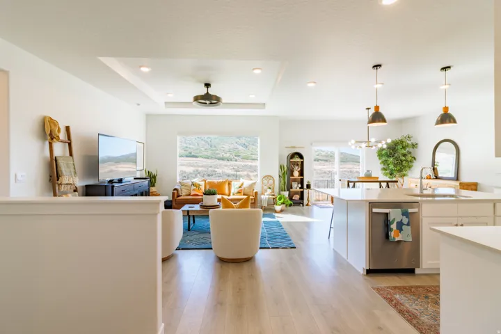 Open-concept living space with light wood-finish flooring, recessed lighting, and a tray ceiling with a built-in fan