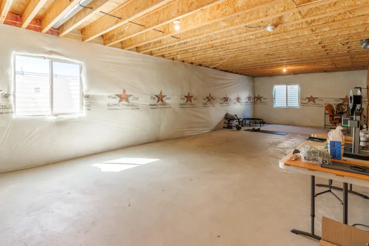 Unfinished lower level with exposed ceiling joists and concrete flooring