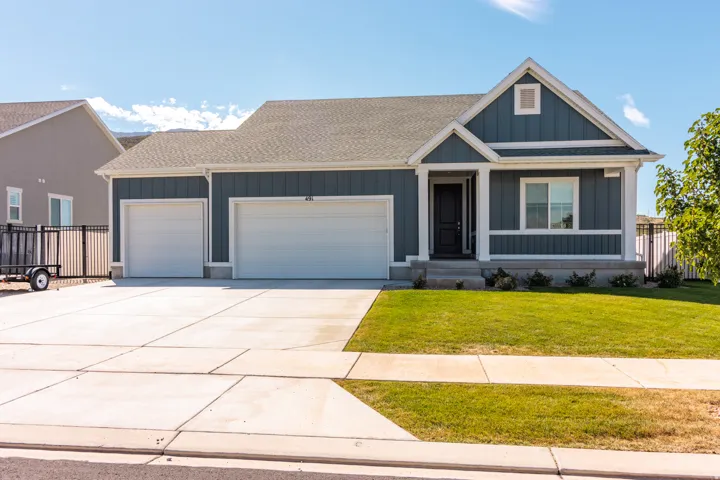 Contemporary single-story residence featuring a two-car garage, covered entry, and a front lawn