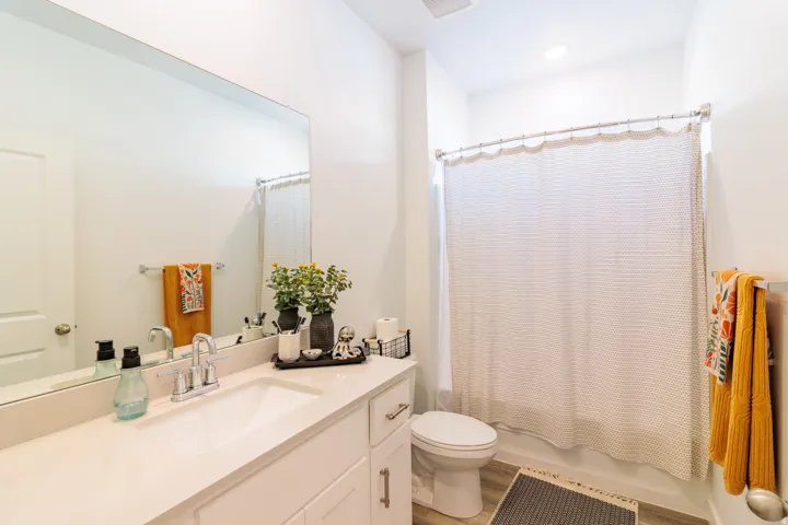 Integrated vanity with a single sink, chrome faucet, and expansive wall-mounted mirror