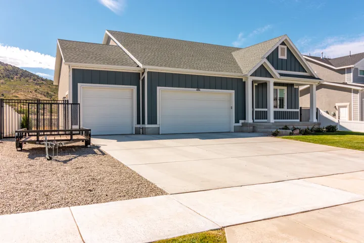 Contemporary exterior with board and batten siding, two-car garage, covered porch entry, and a gravel-covered side yard