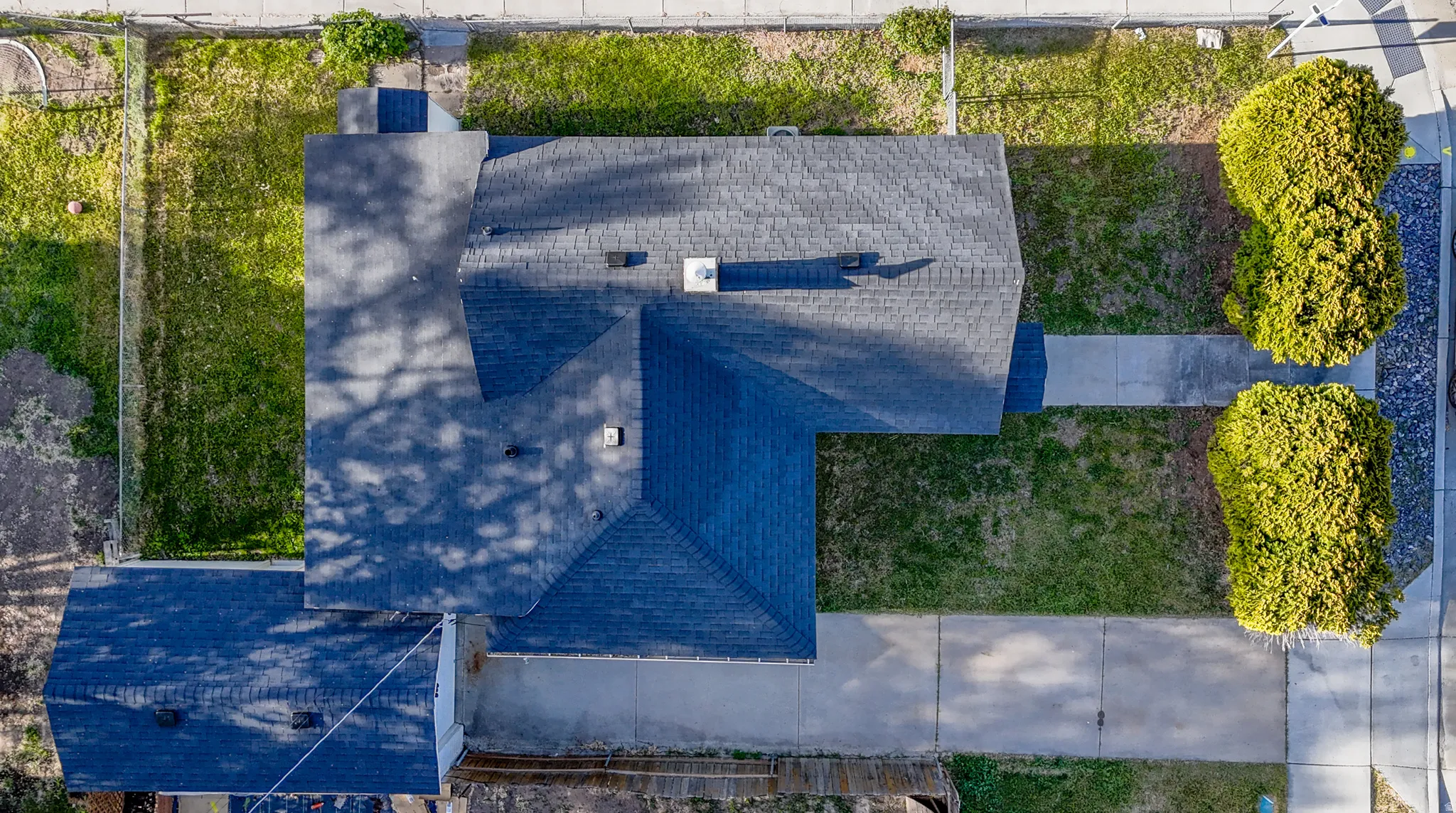 Asphalt shingle roofing, paved driveway, concrete sidewalks, and established landscaping