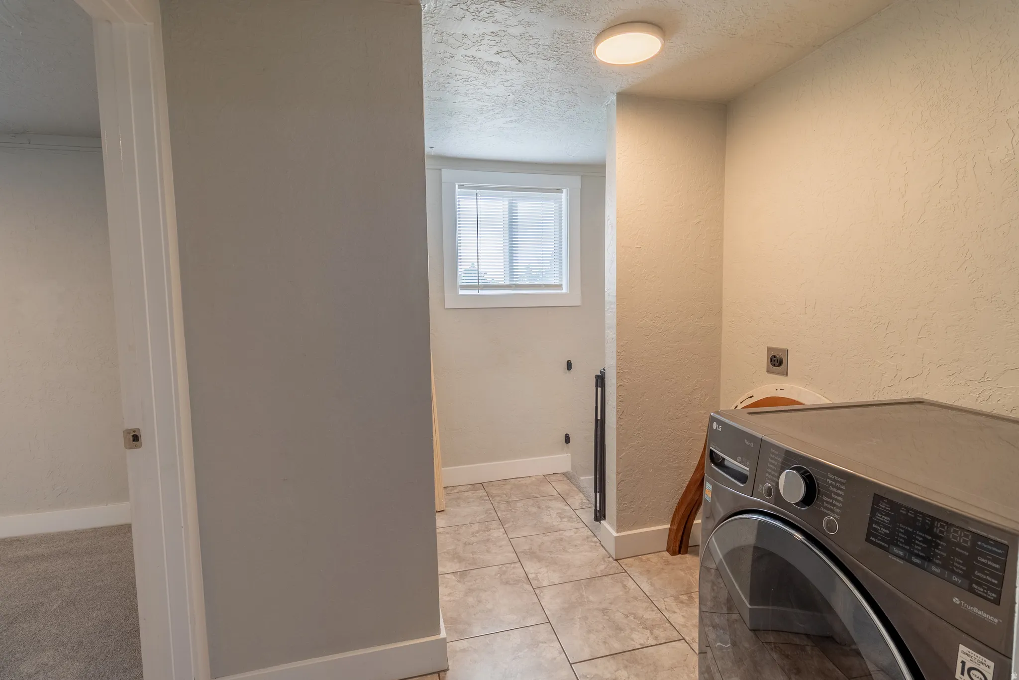Laundry area featuring tiled flooring, a window with blinds, and an overhead flush-mount light fixture