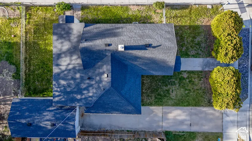 Asphalt shingle roofing, paved driveway, concrete sidewalks, and established landscaping