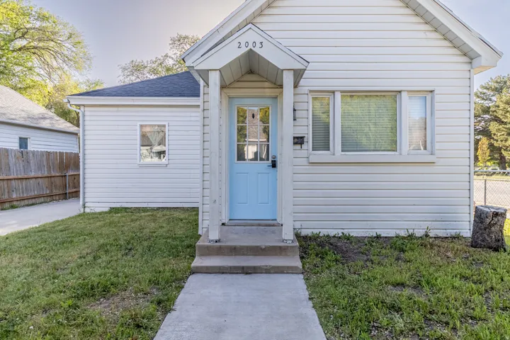 White horizontal siding exterior with a light blue entry door