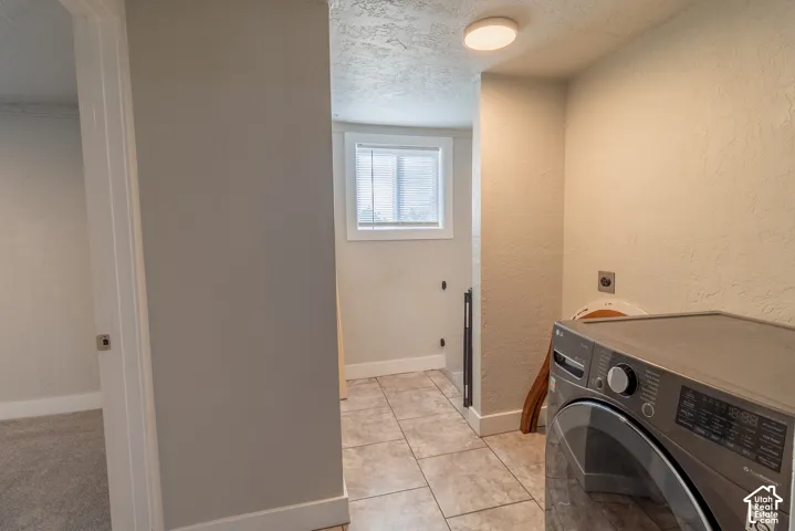 Laundry area featuring tiled flooring, a window with blinds, and an overhead flush-mount light fixture